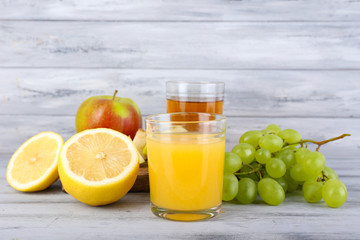 glasses of juice with fresh fruits on grey wooden table