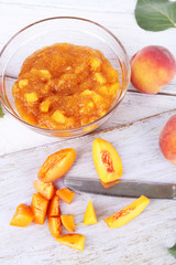 tasty peach jam with fresh peaches on wooden table