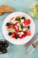 Greek salad and olive oil in plate on wooden background