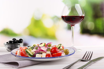 Greek salad served in plate with glass of wine