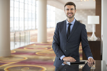 Portrait of young businessman with tablet in hotel lobby
