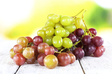 Bunches of ripe grapes on wooden table on natural background
