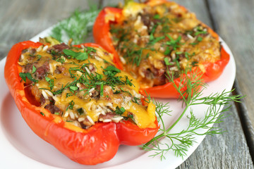 Stuffed red peppers with greens on plate on wooden table