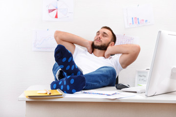 Confident businessman holding his legs in funny socks on desk