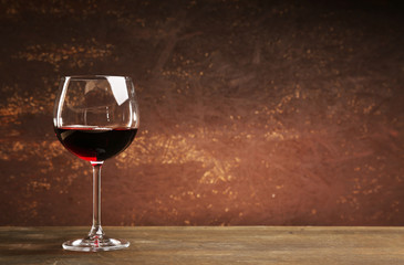 Goblet of red wine on wooden table on wooden wall background