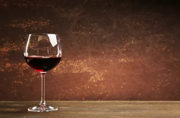 Cercles muraux Vin Goblet of red wine on wooden table on wooden wall background