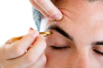 Man removing eyebrow hairs with tweezing. - obrazy, fototapety, plakaty