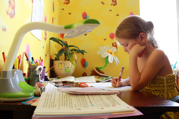 schoolgirl learns lessons at the table