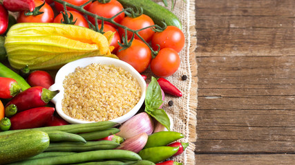 Raw Organic bulgur in bowl and vegetables