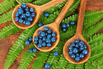 Tasty blueberries in wooden spoons on wooden background