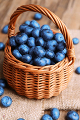 Delicious blueberries in wicker basket on table