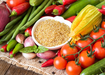 Raw Organic bulgur in bowl and vegetables