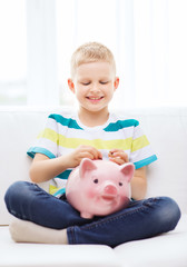 smiling little boy with piggy bank at home
