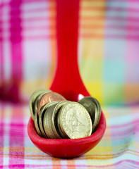 coins inside red spoon put on table