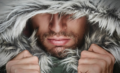 brutal face of a man with beard bristles and hooded winter