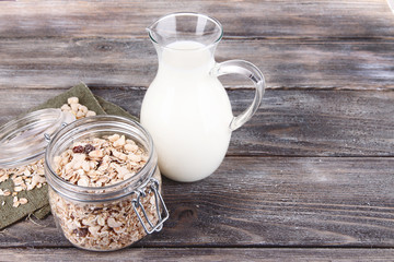 Homemade granola in glass jar and fresh milk in jug,