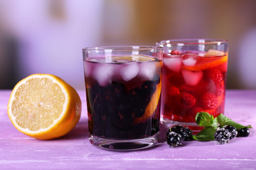 Glasses of cold berry cocktail with lemon on wooden table