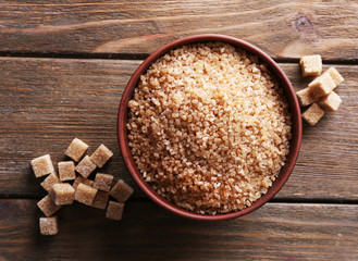 Brown sugar cubes and crystal sugar in bowl on wooden