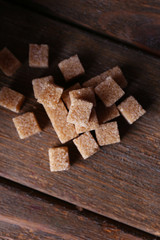 Brown sugar cubes on wooden background