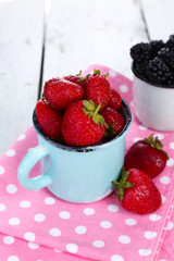 Sweet berries in cup on table close-up