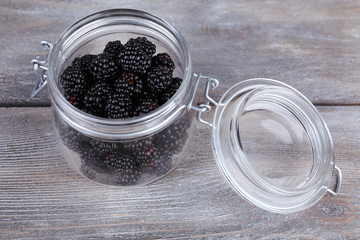 Fototapeta na wymiar Sweet blackberries in glass jar on wooden background