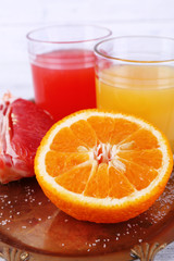 Different sliced citrus fruits and glasses of juice