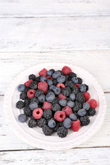 Iced berries on plate, on color wooden background
