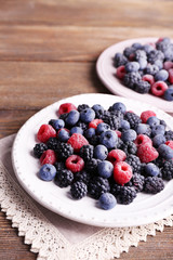 Iced berries on plates, on wooden background