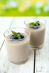 Delicious berry mousse in glasses on table on bright background