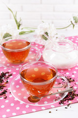 Cups of tea on table on brick wall background