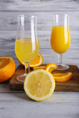 glasses of juice with fresh fruits on grey wooden table