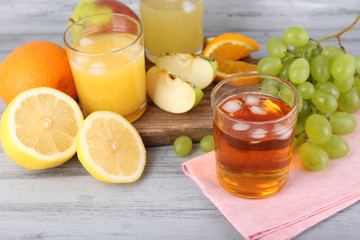 glasses of juice with fresh fruits on grey wooden table