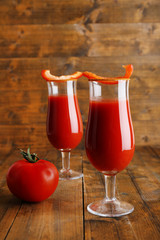 glasses of tasty tomato juice and pepper on wooden table