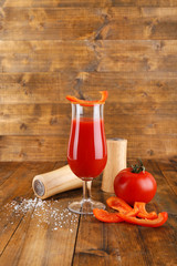 glass of tasty tomato juice and pepper on wooden table