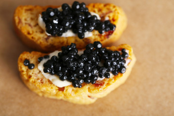 Slices of bread with butter and black caviar on paper