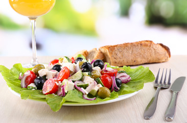 Greek salad in plate and glass of wine