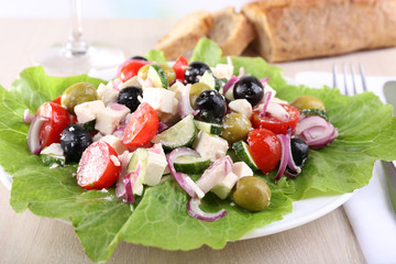 Greek salad in plate served on napkin on wooden background