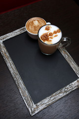 Cups of coffee with cute drawing in cafe