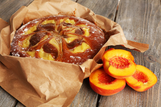 Delicious cake with peaches on wooden table close up