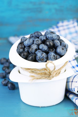 Tasty ripe blueberries in bowls, on wooden table