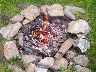 Brennendes Lagerfeuer auf einer Wiese umrandet von Steinen