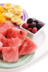 Slices of fruits with berries on plate close up