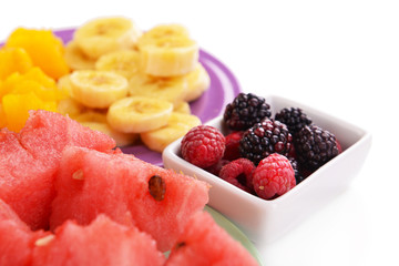 Slices of fruits with berries on plate close up