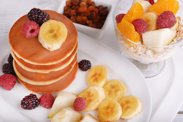 Pancake with fruits and muesli on plate on table close up