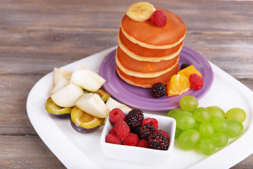 Pancake with fruits and berries on plate on wooden table