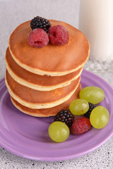 Pancake with berries and glass of milk on table close up