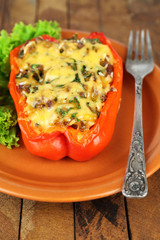 Stuffed red pepper with lettuce on plate on wooden table
