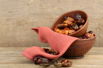 Tasty dates fruits in bowls, on wooden background
