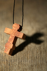Wooden cross with deep shadow on wooden background