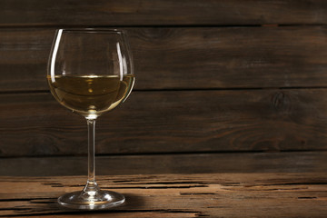 Goblet of white wine on wooden table on wooden wall background